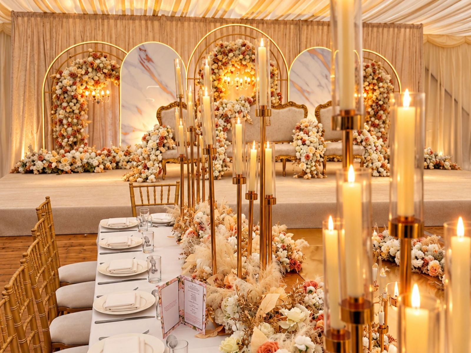 Wedding table setting with gold chairs, candles and floral details.