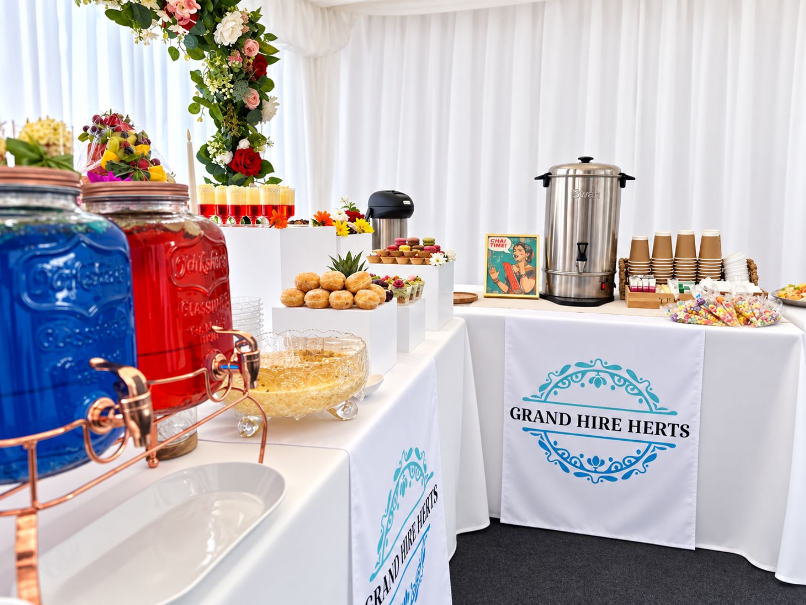 Serving table with drink dispensers and refreshments inside a marquee.